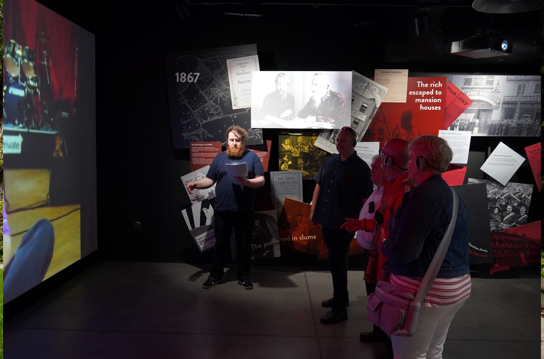 People stand inside exhibition space about John Lennon