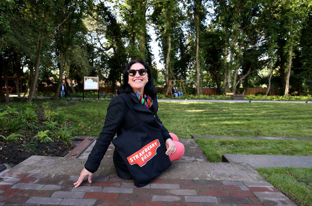 photo of a woman sitting outside at the Strawberry Field garden with a Strawberry Field logo'd tote bag