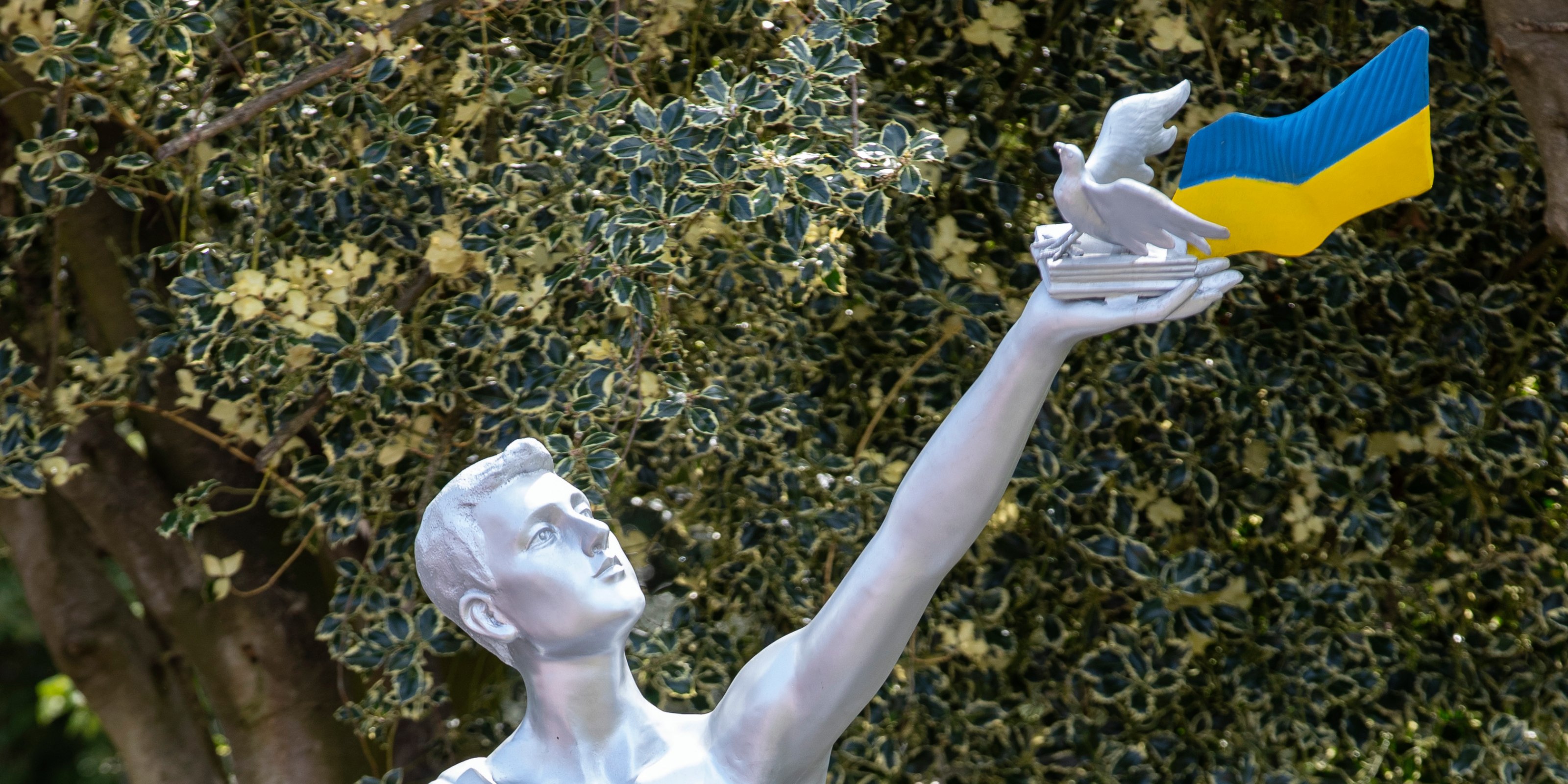 Monument depicting a person holding aloft a book, a dove and Ukrainian flag stands in the garden at Strawberry Field  